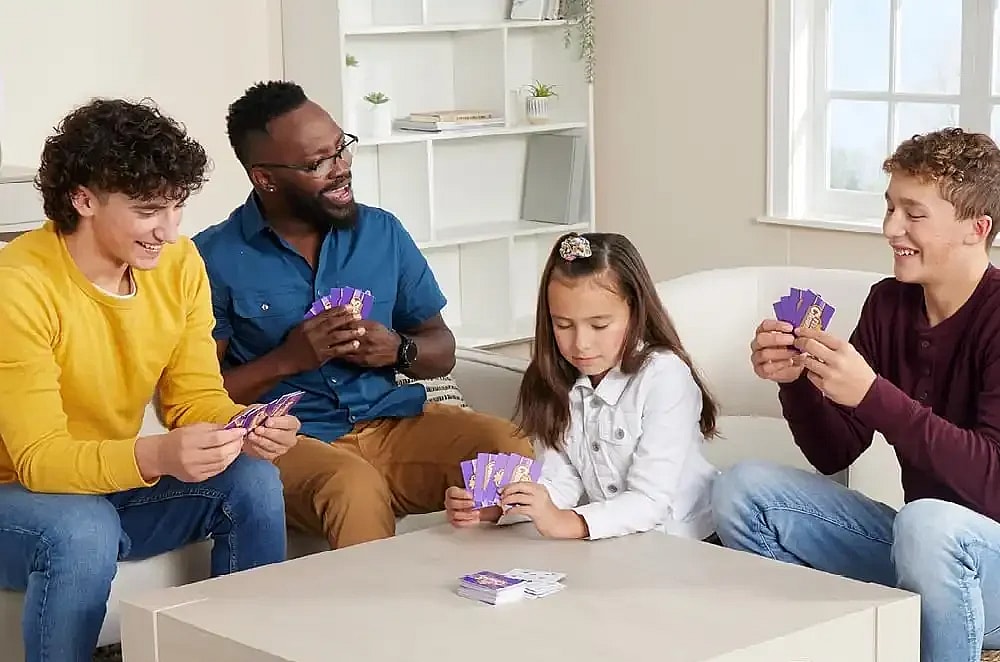 Group of four diverse people playing Five Crowns on a cozy living room table.