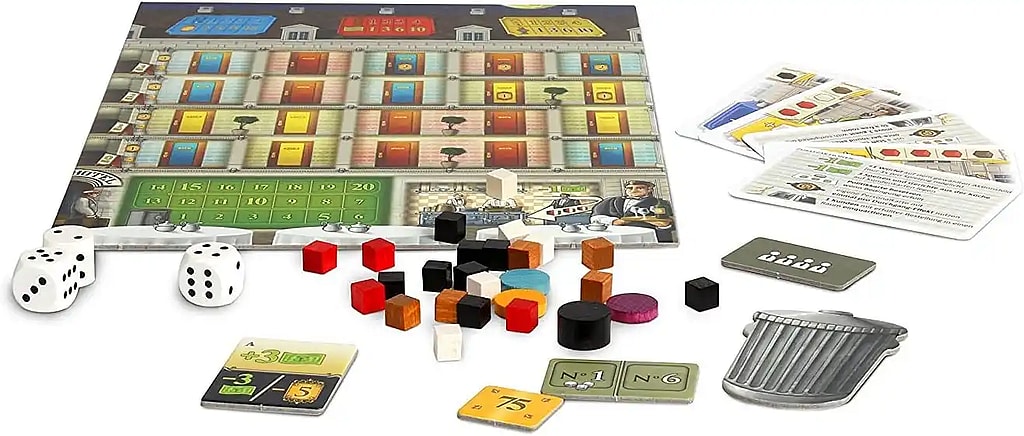 A high-angle photo shows the components of the board game Grand Austria Hotel. The main board depicts a multi-story hotel with colored doors on the upper floor and a green track for a guest seating area below, set above a hotel lobby and restaurant scene. Various components are scattered around the board, including several white six-sided dice, small wooden colored cylinders and cubes (likely customer and resource tokens), several small square and rectangular cardboard tiles displaying numbers and icons (money, action spaces), and a few larger cards with text and symbols (likely objective or staff cards). A gray, garbage-can-shaped token and a small, gray rectangular token with four person symbols are also visible.