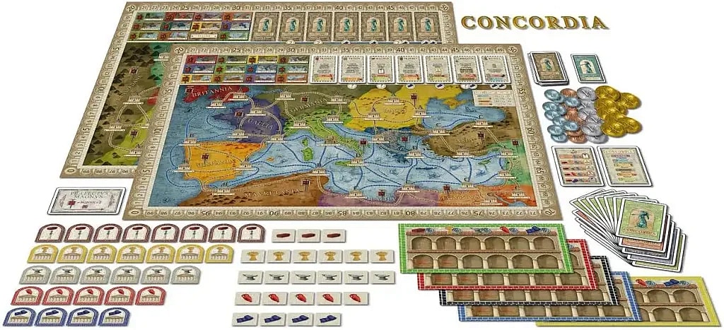 This image displays the full contents of the board game Concordia, spread out for play. The main components include a large map board of the Roman Empire, a long scoring track along the top and sides, stacks of small wooden components representing houses and colonists, various cards (personality, province, and scoring), and coin tokens in different colors. Several player mats (storehouses) are also visible on the lower right, organized by player color.