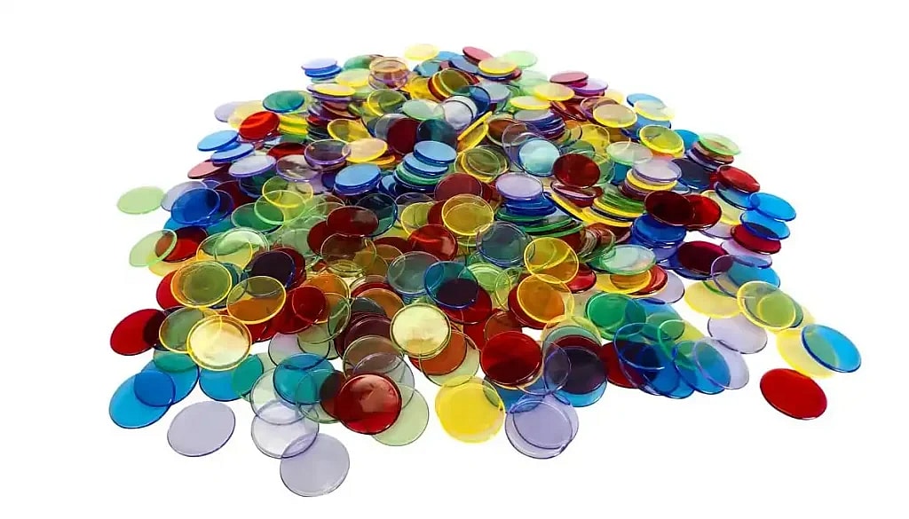A large pile of round, translucent Bingo chips in various colors including red, yellow, green, and blue, suggesting materials used for playing games like Bingo.