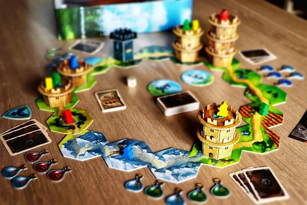 Wandering towers strategy board game setup on wooden table with cards, tokens, game board, castles, and path