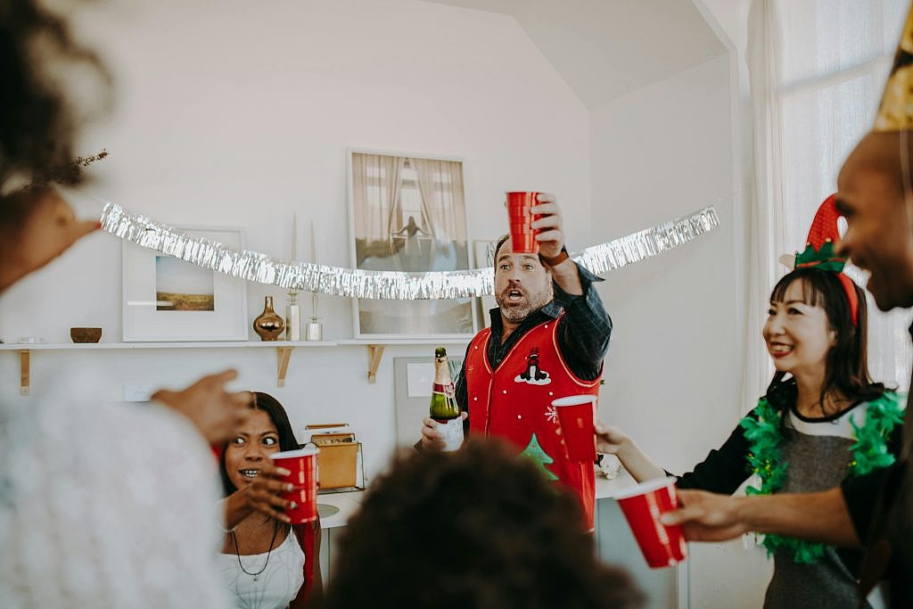 Friends celebrating indoors with red cups and festive decor, enjoying the holiday spirit together.