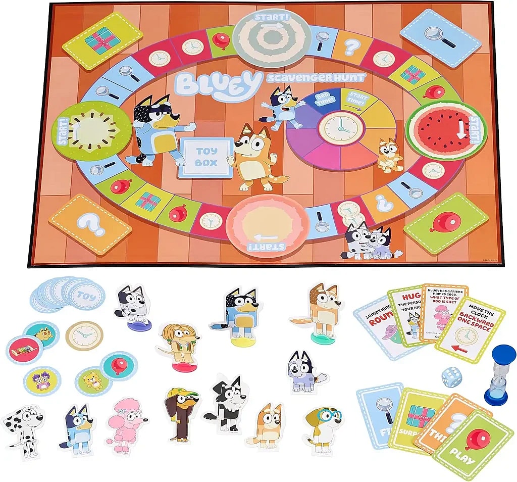 A photo of the Bluey Scavenger Hunt Game set, featuring the game board, character pieces, cards, dice, and sand timer. The colorful game board has a winding path with various spaces, including 'Start', question marks, a 'Toy Box' in the center, and a clock track for the time token. Scattered around the board are character tokens of Bluey, Bingo, their family, and friends. The various card decks for the game are also visible, including 'Find', 'Play', 'Think', and 'Surprise' cards.