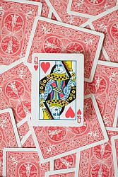 Close-up of Queen of Hearts surrounded by scattered red back playing cards.
