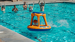 Group of friends enjoying a summer pool party with an inflatable basketball hoop, showcasing fun and togetherness.