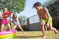 Children enjoying a water gun fight in a sunny summer backyard.