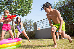 Children enjoying a water gun fight in a sunny summer backyard.