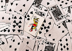 A vibrant joker card stands out in a scattered deck of monochrome playing cards.