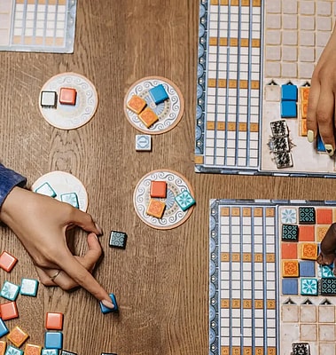 bg photo Hand pointing to a classic board game setup, with boards, cards, tokens, and chips