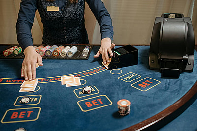 Casino dealer organizing cards and chips on a gaming table during a blackjack game.