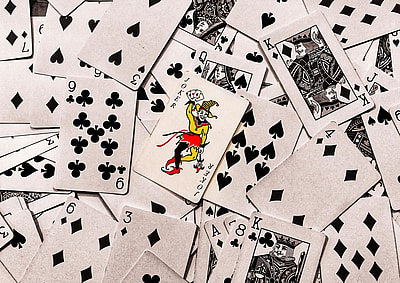 A vibrant joker card stands out in a scattered deck of monochrome playing cards.