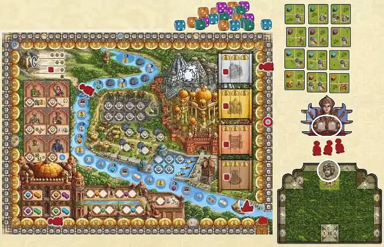 (Rajas of the Ganges): A flat-lay of the game components, dominated by the large, ornate main board showing the River Ganges flowing through a landscape with various worker placement and market spaces. Components visible include a central pile of colorful, six-sided dice, small square green Province tiles laid out to the right of the board, a player home board with a green grid, and a few wooden worker meeples and character standees.